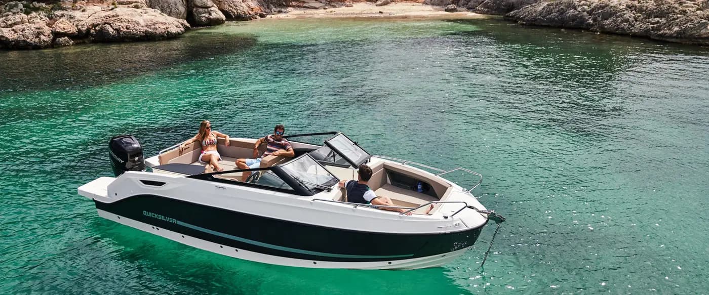Bateau à moteur au mouillage dans une crique, trois personnes à bord